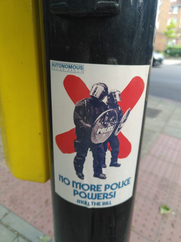 Sticker on lampost which reads 'NO MORE POLICE POWERS! KILL THE BILL'.