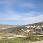 Photo of a white Israeli buildings, perhaps a settlement, set against a Palestinian landscap