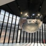 Floating sliver sphere reflecting an art gallery