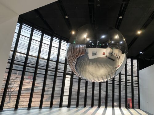 Floating sliver sphere reflecting an art gallery