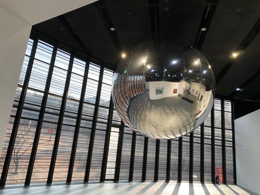 Floating sliver sphere reflecting an art gallery