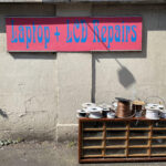 Sign with 'Laption + LCD Repairs' in gaudy blue on pink with coils of wire below