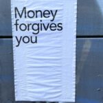 Paper pasted to wall which says, "Money forgives you"