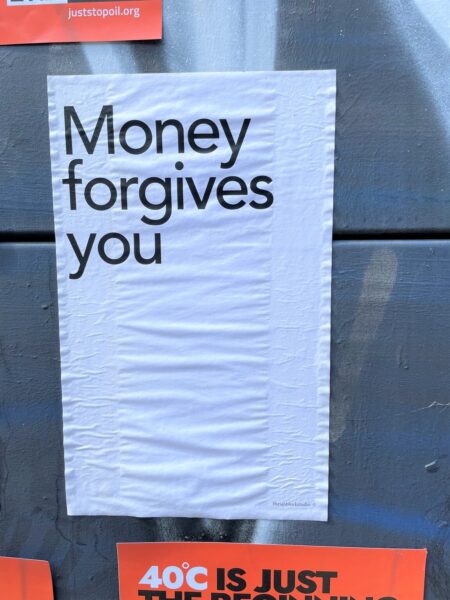 Paper pasted to wall which says, "Money forgives you"
